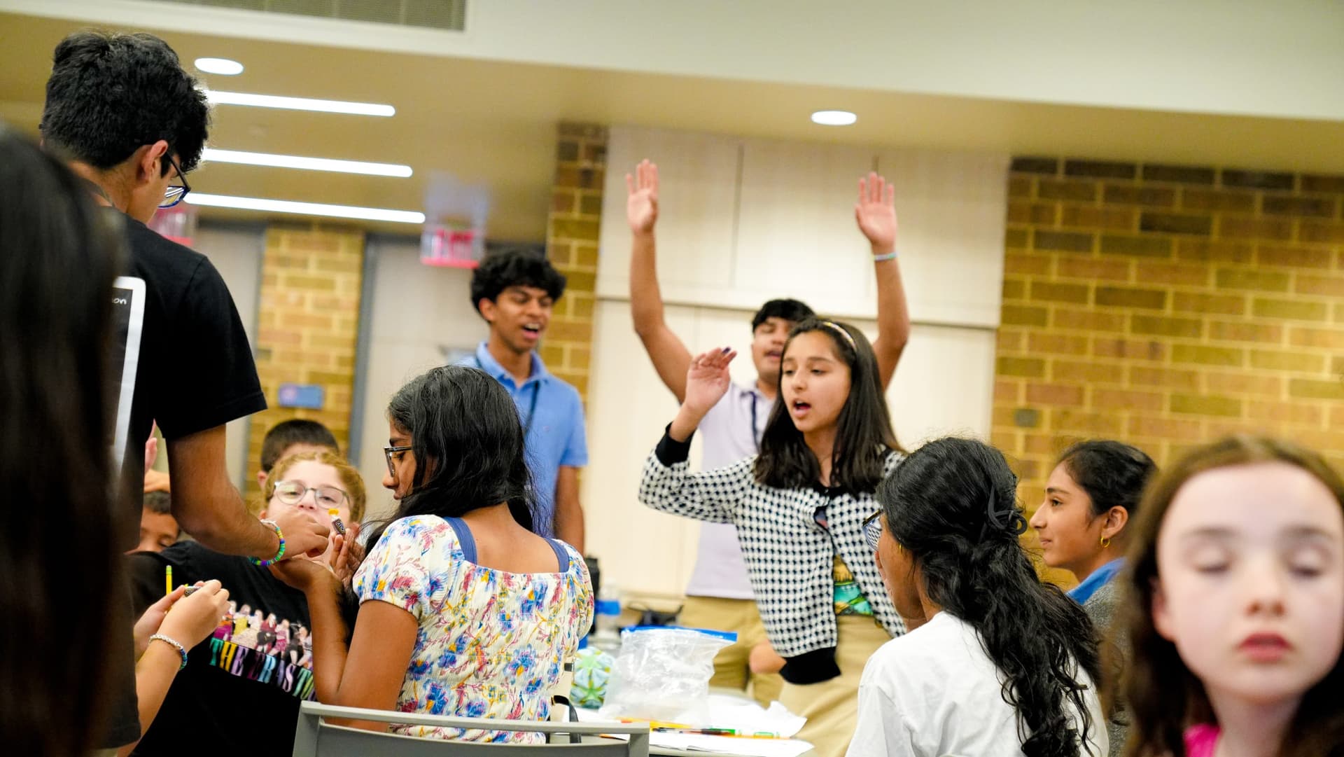 Campers raising their hands to answer a question at a 2024 camp session