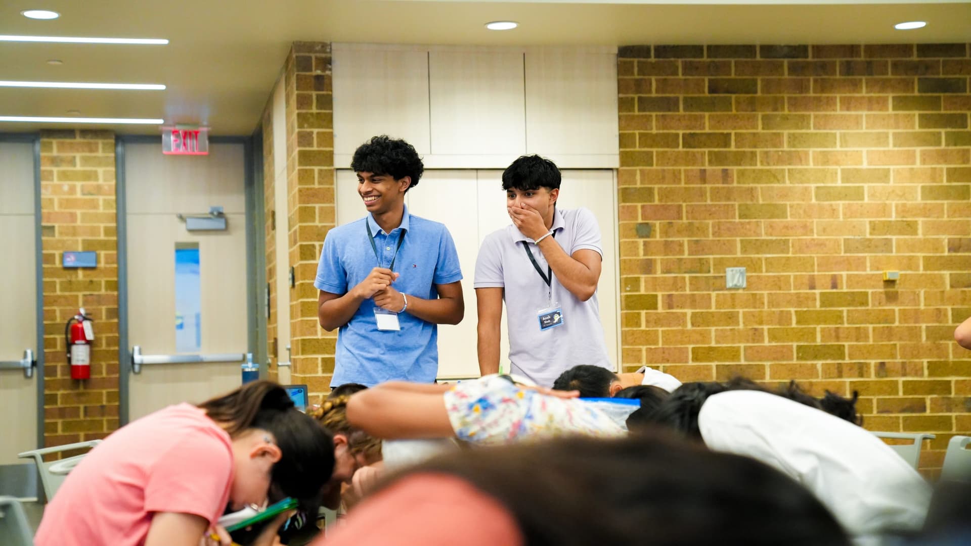 Two BizBuzz instructors laughing while campers work on an activity