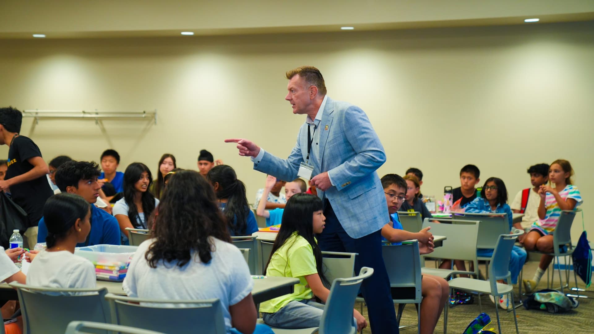 A visiting speaker in a light blue suit calling on a camper